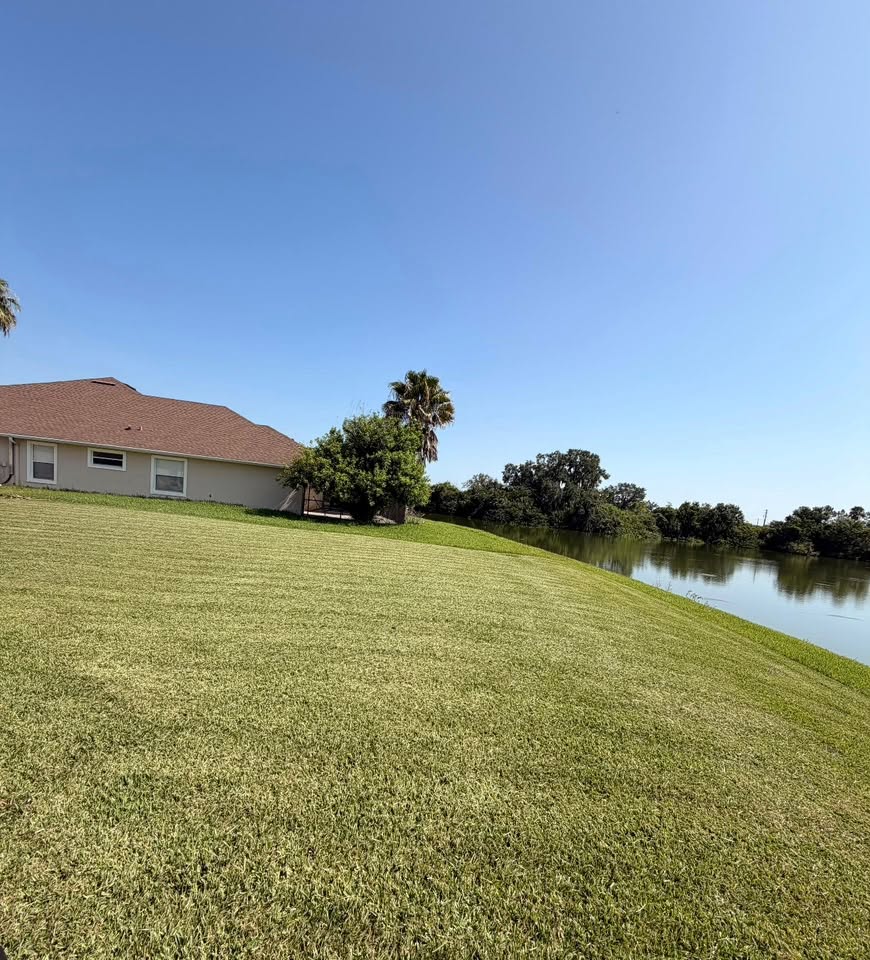Large sloped lakefront lawn maintained by Green Touch Landscaping